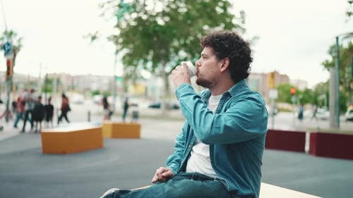 Clouse-up, man sitting and drinking coffee on busy street on modern city background