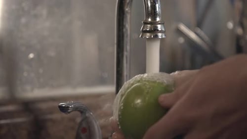 Thorough Cleaning Of Green Apple Using One Hand On The Kitchen Sink. -medium shot