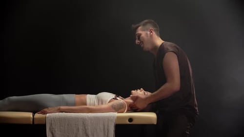 Osteopath Gently Manipulating Patient's Neck on Massage Table