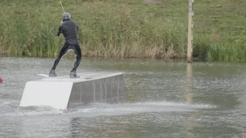 Wakeboarder Glides and Jumps on Lake Ramp