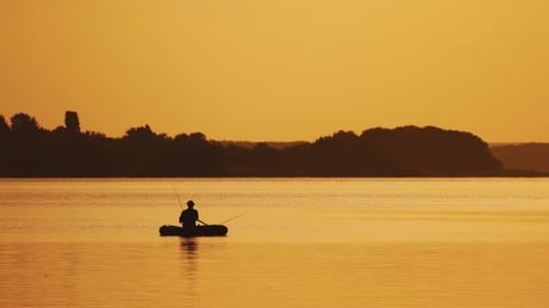 Toller Blick auf den Sonnenuntergang am Abend und einen Mann in einem Boot beim Angeln.