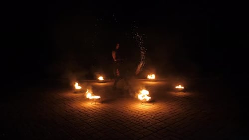 Man fire dancing with flaming props at night