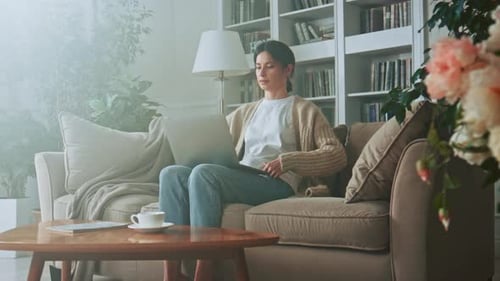 Woman Using Laptop on Couch Indoors