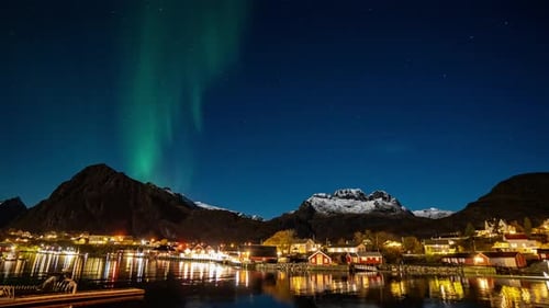 time lapse of northern lights over Sørvågen village on lofoten islands with mountains on background