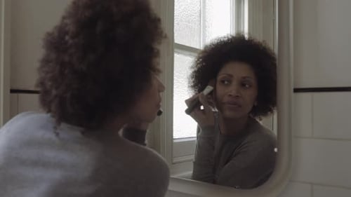 Woman Applying Makeup in Bathroom Mirror