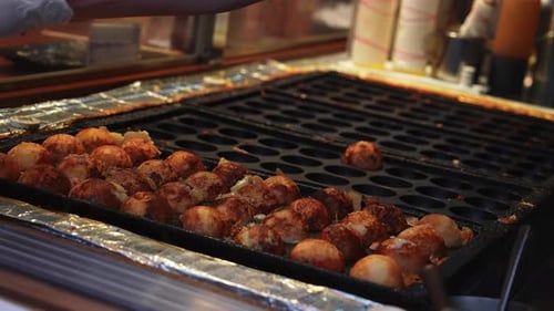 Primer plano de Takoyaki cocinando en un puesto callejero de Tokio por la noche
