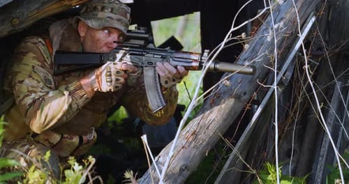 Man Aims Rifle in Camouflage in Rural Setting