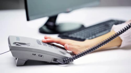 Hands Using Office Phone Beside Computer Keyboard