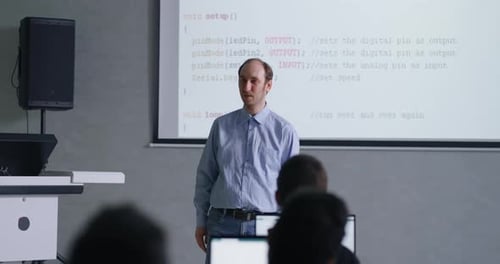 MiddleAged Male Teacher Communicating With School Student In Classroom Studying Programming