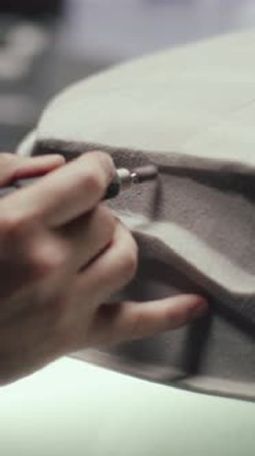 Un concepteur automobile senior utilise un outil rotatif pour perfectionner la sculpture d'un prototype de voiture