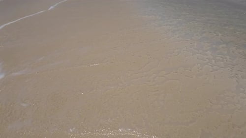 Hochgekippte Wellen stürzen auf eine tropische weiße Sandbank, die Leute genießen den Strand im Hintergrund