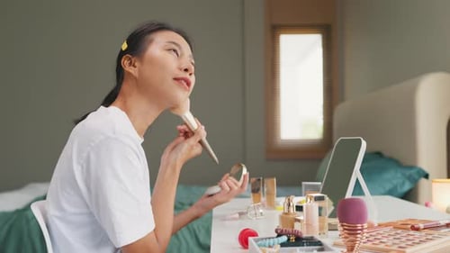 Young happy Asian girl beauty blogger looking at mirror makeup use makeup brush apply brush powder.