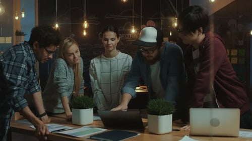 Team Collaborates on Laptop in Modern Office