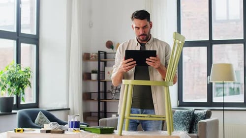 Man looks at tablet near upcycled painted chair