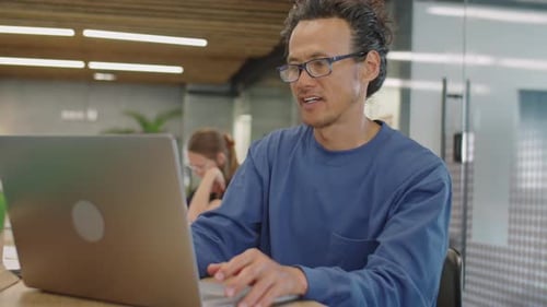 Man Typing on Laptop in Modern Workplace