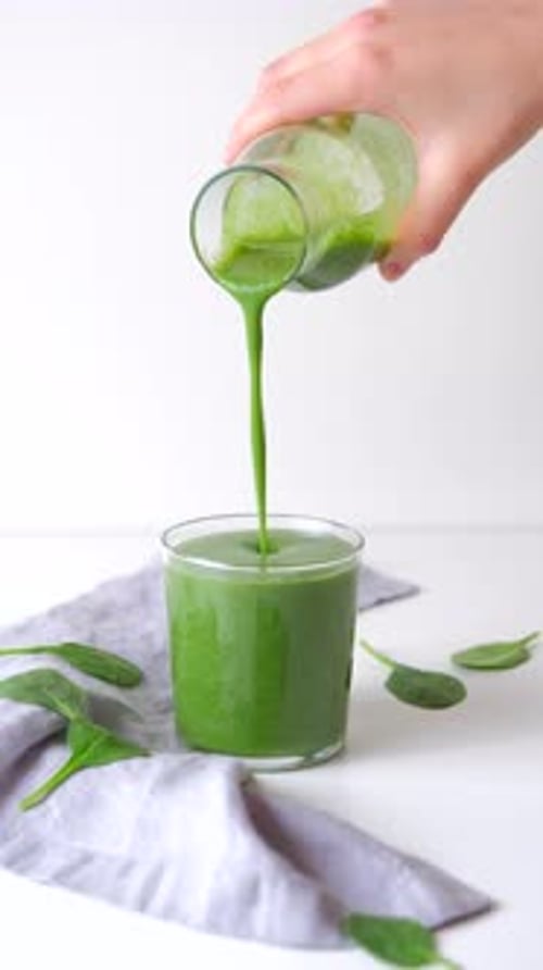 Green Spinach Smoothie Or Juice. Pouring Homemade Detox Green Smoothie In Glass