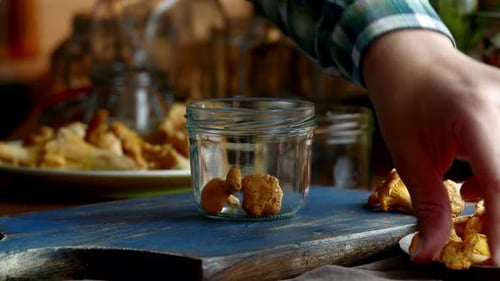 Chanterelle Mushrooms Being Placed into Glass Jar