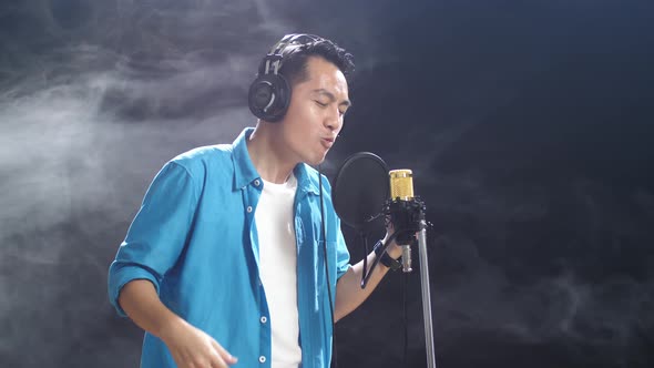 Side View Of Asian Man With Headphone Rapping Into A Condenser ...