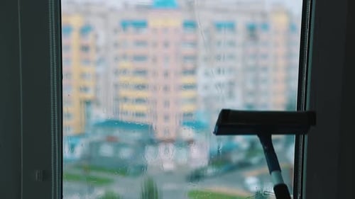 Window Cleaning with Squeegee Overlooking Colorful City