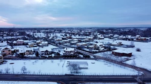 Baltic aerial residential landscape, Drone fly snow covered rural town, sunset sky