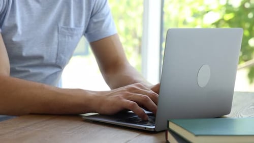 Man Typing on Laptop Computer at Wooden Table