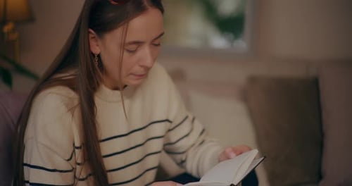Woman Reading Book on Sofa at Home