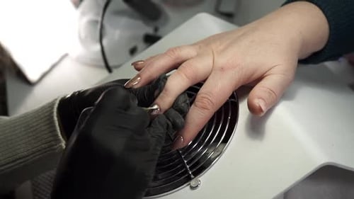 Close up view. Manicurist works with nail file in a beauty salon.