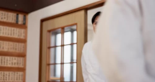 Man in White Uniform Bows in Martial Arts Dojo