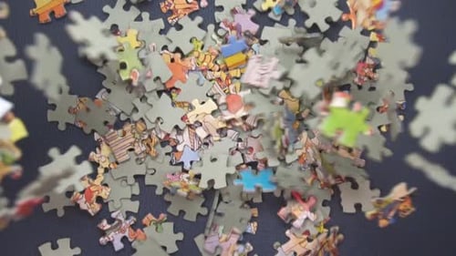 Many Puzzle Pieces Falling Down On Dark Blue Surface - high angle, slow motion