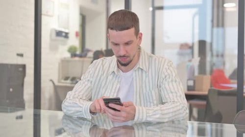 Creative Young Man Celebrating Success on Phone in Office