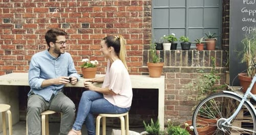4k video footage of a young couple sitting outside a cafe together during a date