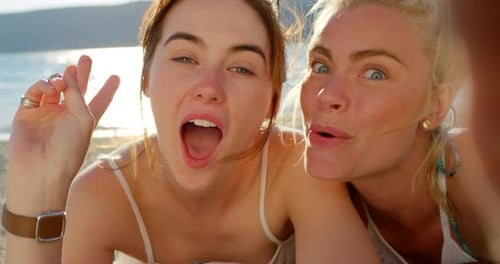 4k video footage of two friends taking selfies while lying on the beach