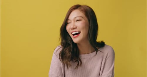 Smiling Woman Shakes Her Hair on Yellow Background