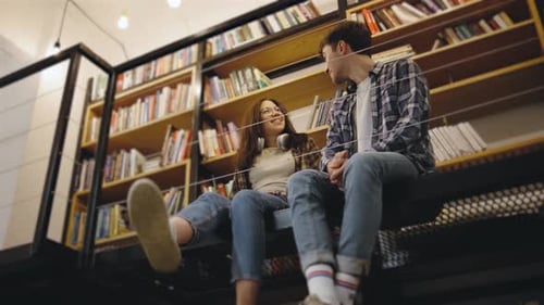 Young Couple Enjoying a Quiet Moment Together in a Cozy Library Filled with Books During the