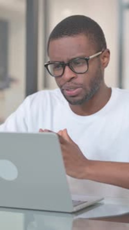 Focused Man Video Conferencing on Laptop Indoors
