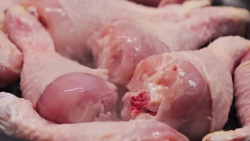 Close-up of raw chicken drumsticks steaming in pan