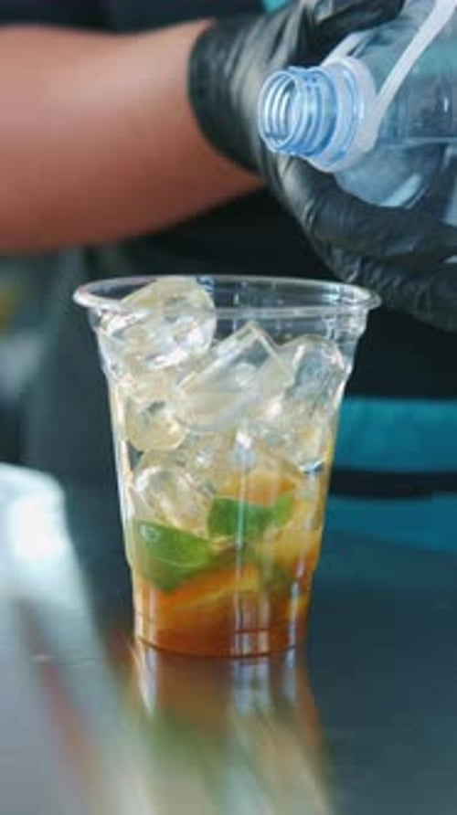 Preparation of a Refreshing Drink with Ice and a Medley of Citrus Fruits for Enjoyment
