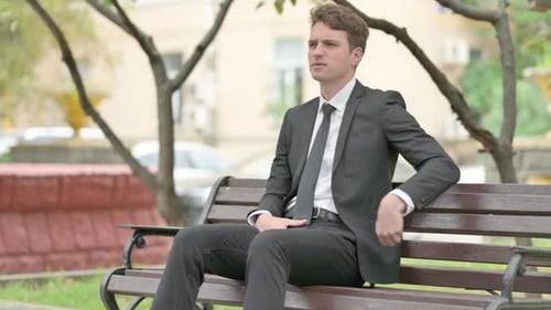 Man in Suit Massaging Back on Park Bench