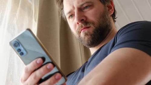 Man Uses Smartphone Indoors, Concentrating