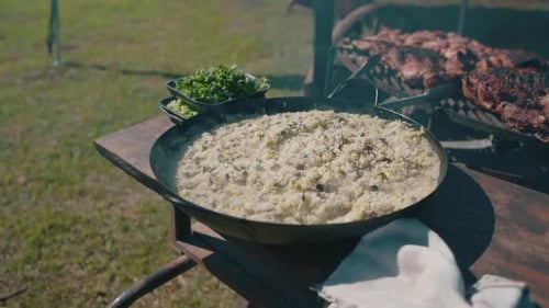 Close-up of steaming rice and fresh herbs at an outdoor Argentinian barbecue feast. Gastronomy.