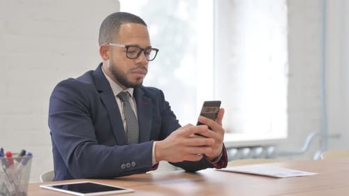 Young Adult Man Uses Smartphone in Office