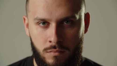 A Bearded Guy Stands on a Gray Background and Looks Attentively Into the Camera Studio Shot of a