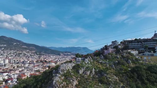 Aerial Video of a Funicular Ascending the Mountain With a Scenic City View and a Blue Forest in the