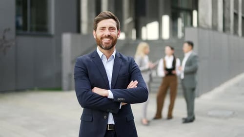 Portrait a confident handsome businessman in a suit standing looking at camera near office building.