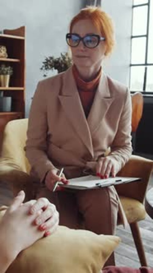 Middle-Aged Therapist Listening to Unknown Patient and Writing on Clipboard