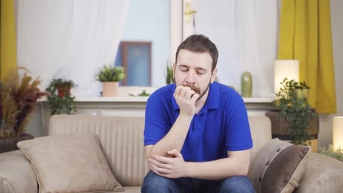 Worried Man Sits On Couch In Bright Living Room