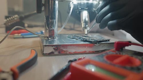 CloseUp of Technician Repairing Circuit Board Using Microscope and Tools