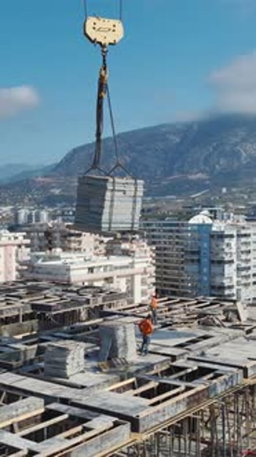 Vertical Drone Footage Crane Lowering Concrete Panels Onto Building Frame