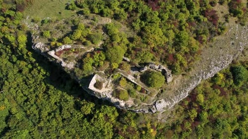 Aerial view of medieval fortification ruins, on a cliff in the forest by drone