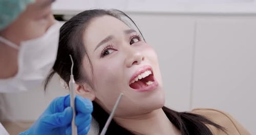 Slowmotion dental treatment moment showing asian female adult patient smiling during oral checkup